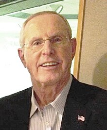 Head shot of Tom Coughlin wearing a suit and smiling.