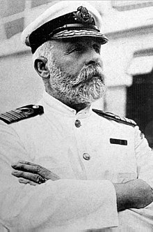 Photograph of a bearded man wearing a white captain's uniform with crossed arms