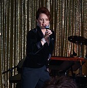 A red-haired woman wearing a dark blue shirt and pants is performing