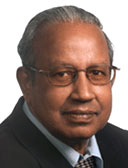 Portrait of a middle-aged Indian man with grey hair wearing spectacles and a suit and tie.