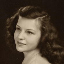 a tight headshot sepiatone image of a young woman with long flowing hair in 3/4 profile