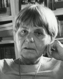 Black and white Press photo of a woman with serious expression, and short, smooth haircut with a long, thick fringe (bang).