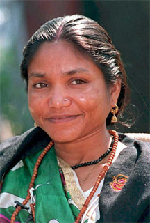 Head and shoulder photograph of woman half-smiling past camera. She wears a brown necklace and her black hair is pulled back.