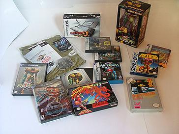 Boxes of the Metroid games, plus a Samus bobblehead figurine, and a T-shirt in its package.