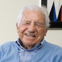 an image of an older man in light blue sweater smiling