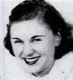 A young white woman, smiling, with dark wavy hair in a side part.
