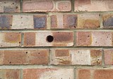 Hole in brick wall provides a path for rain penetration.