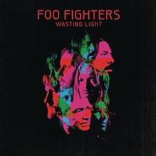 A collage of green, blue and pink face pictures of the Foo Fighters members against a black background. Above it is the title "FOO FIGHTERS – WASTING LIGHT" in red letters.
