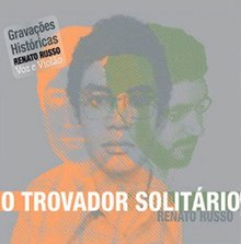 Grey square with three overlapped pictures of Renato Russo's bust (one green, one orange and one dark grey). 'O Trovador Solitário' is written in capital letters and 'Renato Russo' is written in a smaller fonte right below and to the right. A sticker at the top-left corner of the image says 'Gravações Históricas Renato Russo Voz & Violão', which translates as 'Historic Recordings Renato Russo Voice & Acoustic Guitar'