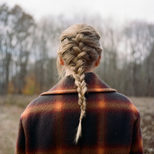 Cover artwork of evermore, a picture showing Swift in braided hair from behind, in front of a barren field