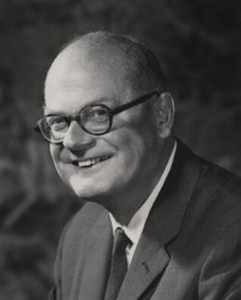 middle aged white man, mostly bald, clean shaven, wearing spectacles, grinning cheerfully