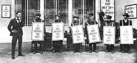 Tall young man on the left with a team of six men in sandwich-boards advertising "13 Soap - unlucky for dirt"