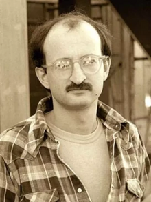 Black-and-white photograph of Jim Rivaldo. He is a man with glasses and a mustache.