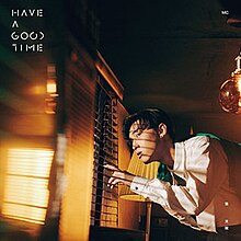 A man wearing a white dress shirt with a tie is seen looking out the window through small cracks in the blinds