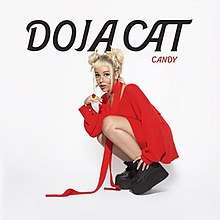 A photo of Doja Cat with a double bun hairstyle, a red jacket, and black shoes, kneeling in front of a white backdrop. Above her is large black text that spells out her name. To its bottom right is smaller text, shown in red, that reads "Candy".
