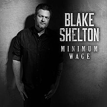 The artwork for Blake Shelton's single "Minimum Wage", featuring a black and white image of Shelton standing against a wall; to the right of him appears the words "Blake Shelton" and "Minimum Wage" is all-caps fonts.