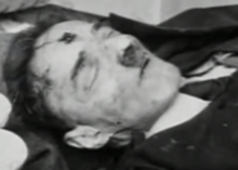 Dead body with a toothbrush moustache and an apparent gunshot wound to the forehead
