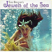 Cover image for Jewels of the Sea. There is a white band with text above a photograph. On the white, mid-size black text says "Les Baxter's". Directly underneath, larger purple text says "Jewels of the Sea". Under that, small black text says "Titillating Orchestrations for Listening and Loving". The photograph depicts a Caucasian woman with brown hair from the waist up, posing underwater among bubbles and kelp strands. Her hair floats in the water. She is apparently nude but her chest is hidden by her crossed arms and some strategically placed kelp. She has glamorous makeup and large pieces of silver jewellery in her hair and around her neck.