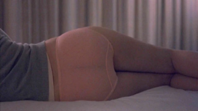 The backside of Charlotte lying down in a gray sweater and transparent pink panties.