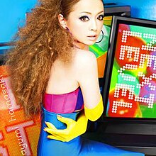 A picture of a woman wearing a latex costume surrounded by television screens.