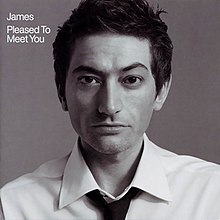 A black-and-white close-up of a man wearing a white shirt and black tie against a grey background