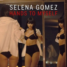 Selena Gomez in a two-piece black lingerie trying on a white shirt whilst looking at her reflection through a glass door.