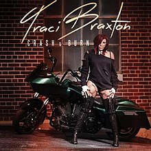 Woman with off shoulder leotard and thigh high boots standing in front of a green motorcycle.