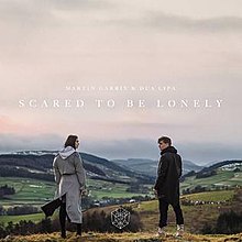 Martin Garrix and Dua Lipa stand on a hill with a landscape backdrop looking at one and other. Garrix wears a black hoodie while Lipa spots a grey coat. Their names appear in the middle while the song's title, "Scared to Be Lonely" appears below it.