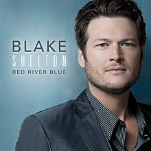 The cover consists of Shelton wearing a grey suit against a blue background. The artist's name and album title is placed beside him on the left: "Blake" and "Red River Blue" are colored black, and "Shelton" is colored white.