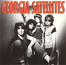 A black-and-white photo of the band. The album title appears above the band in red text.
