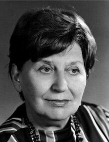 Publicity shot of dark-haired, middle-aged woman with short, bouffant hairdo and a half-smile