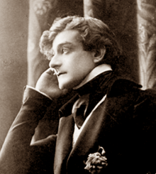 young white man, clean shaven, with mid-length dark hair seen in left profile