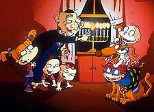 A cartoon of an elderly man lighting a Menorah. He is bald and wearing a Kippah. At his feet are three toddlers; two are on their hands and knees, the other is standing. To their right are two infants sitting on a large brown dog. One infant is bald and wearing a nappy; the other is wearing a t-shirt and shorts.