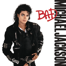 A man in his late twenties stands and looks forward. His hair is curly and black. He is wearing a black jacket that has several buckles and pants. The background is white and beside him are the words "Michael Jackson" in black capital letters, and over them, "Bad" in red.