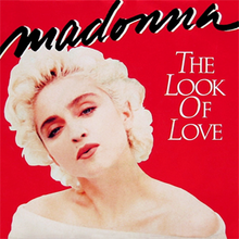 Madonna looks towards the front and tilts her head to the right. She is wearing a white dress, with bare shoulders.