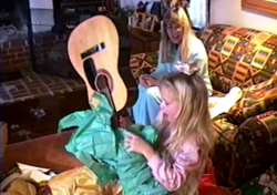 Taylor Swift is unwrapping her gift to find a guitar.