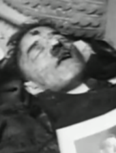 Dead body with a toothbrush moustache and an apparent gunshot wound to the forehead