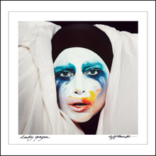 Gaga with paint on her face and looking at a camera