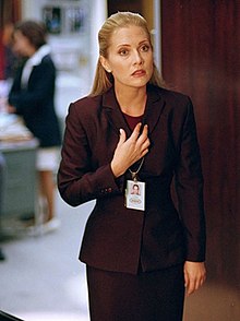 White woman with blonde hair in a reddish business suit
