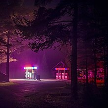 A night shot of a glowing gas pump in between trees