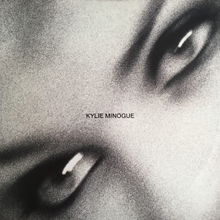 A black-and-white, and motion-blurred image of a woman's (Kylie Minogue) eyes. The song title and woman's name is superimposed on the image.