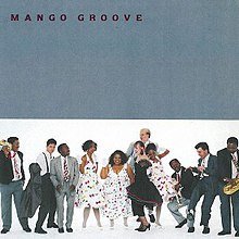 The top half of the album cover is grey; the name 'Mango Groove' appears in black serif type in the upper-left corner. In the lower half of the cover, the band's 11 members are dressed in festive, jazzy clothing. They are smiling and looking at each other as they each strike a different pose.