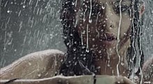 A portrait of a young brunette woman taking a shower.