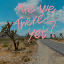 A picture from the side of a road in an American desert with "Are We There Yet?" written over the top in pink writing