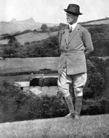 Clean-shaven white man in early middle age standing in front of a rural building