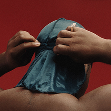 ASAP Ferg adjusting his durag on a red background.