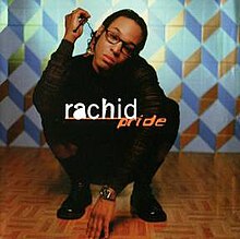 Rachid crouches in front of blue wallpaper