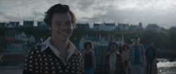 Harry Styles smiling with five other people in the background.[95][98]