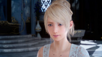 A blonde-haired, blue-eyed woman in a white dress, standing in a well-furnished room in daylight. She looks at something off camera with a fatigued expression.