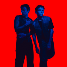 Marcus and Martinus facing different directions bathed in a blue light against a bright red background